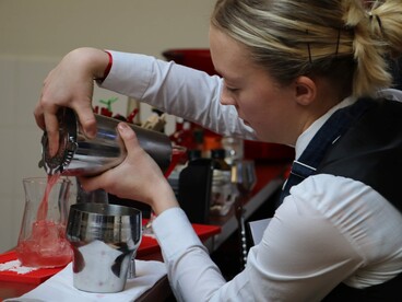 Une lycéenne du lycée hôtelier réalise un cocktail au shaker et le verse dans un verre