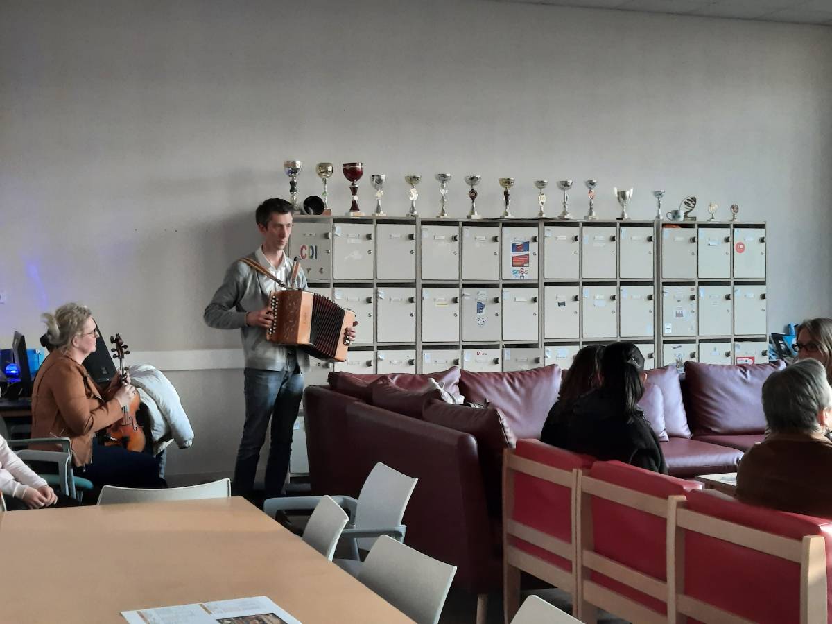 Deux personnes au violon et à l'accordéon accompagnent des lectures en face d'un public