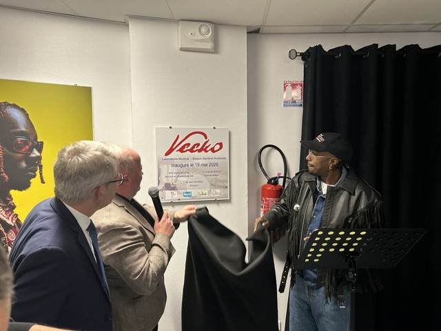 Le batteur Veeko découvre une plaque portant son nom sur un mur, d'autres personnes l'entourent