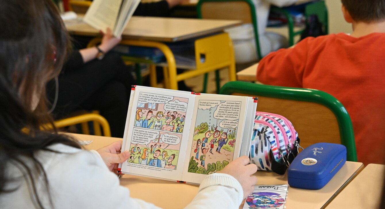 Une élève lit un livre à son pupitre pendant le quart d'heure de lecture national