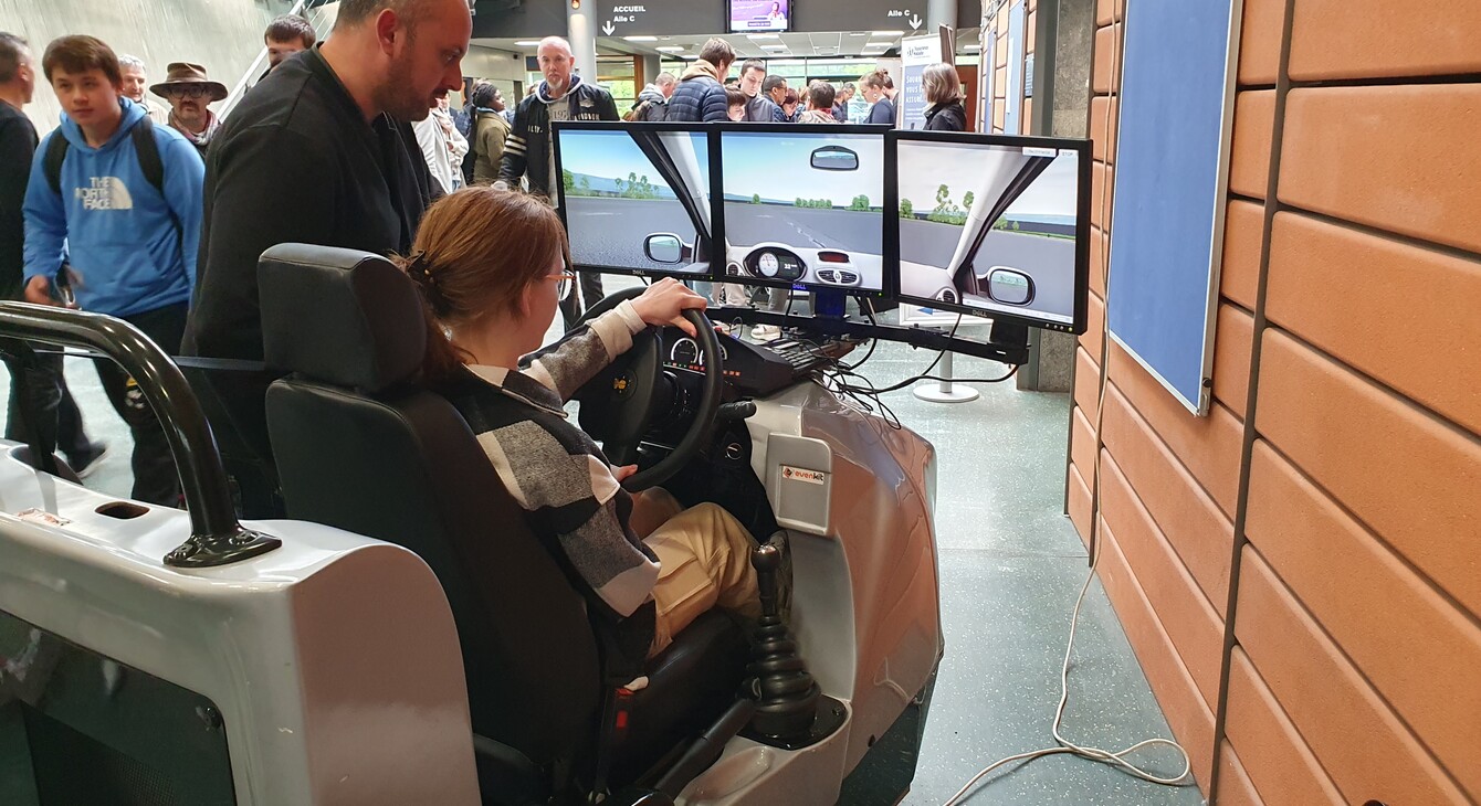 Une élève est dans un simulateur de conduite, accompagnée par un encadrant dans le cadre de l'animation sur la sécurité routière