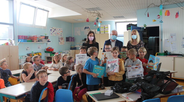 Les élèves de CP, CE1 et CE2 de l'école La Fontaine à Saint-Floris sont dans leur salle de classe et reçoivent des livres et des jeux dans le cadre de la remise de prix du concours ELVE EPS Numérique