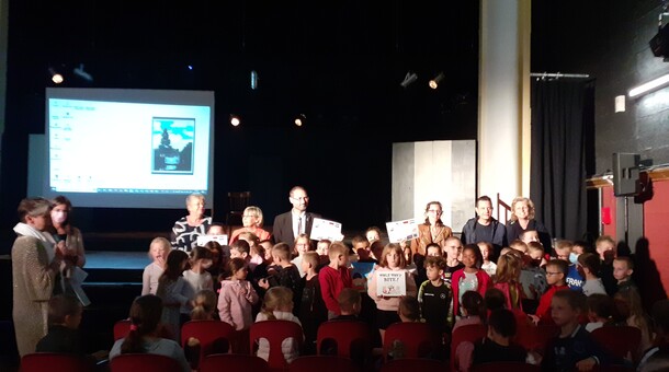 Les élèves de CE1 et CE2 de l'école Prévert à Lillers sont dans une salle de spectacle et reçoivent des livres et des jeux dans le cadre de la remise de prix du concours ELVE EPS Numérique