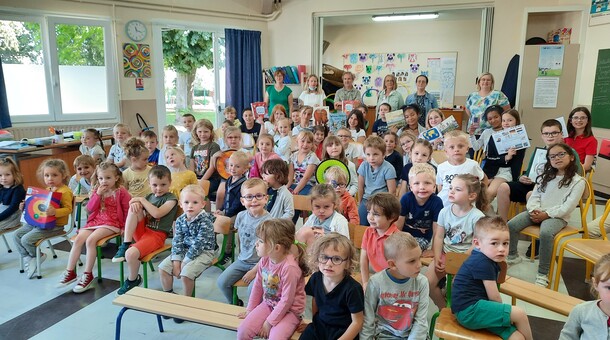 Les élèves de la maternelle et de CM2 de l'école Verlaine à Longuenesse sont dans une salle de classe et reçoivent des livres et des jeux dans le cadre de la remise de prix du concours ELVE EPS Numérique