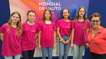 Les collégiennes lauréates du prix "Elles bougent" sont devant une affiche du mondial de l'automobile avec une marraine de l'association