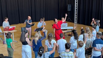 Des élèves s'entraînent au chant avec une chanteuse professionnelle et un orchestre