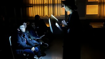 Une professeure fait une lecture dans le noir, devant des collègiens