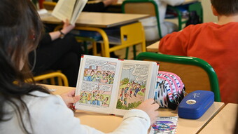 Une élève lit un livre à son pupitre pendant le quart d'heure de lecture national