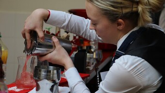 Une lycéenne du lycée hôtelier réalise un cocktail au shaker et le verse dans un verre