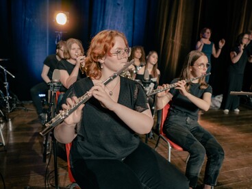 Les élèves de l'option musique du lycée Louis Blaringhem de Béthune sont sur une scène, au premier plan se trouvent 2 élèves qui jouent de la flûte à bec 