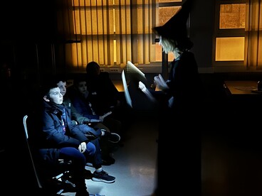 Une professeure fait une lecture dans le noir, devant des collègiens